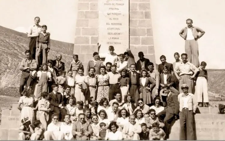 La imagen muestra a un grupo de personas, identificadas en el texto circundante como inmigrantes judíos de Europa del Este en 1938, junto a un monumento que la búsqueda visual no ha podido identificar positivamente. El texto de la imagen explica que la "Tnua de la Noar Hatzioni" y la Sinagoga de Quito forman parte de la tradicional Comunidad Judía de Ecuador, que se fundó en 1938