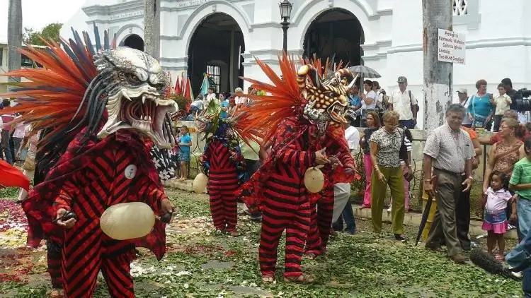 La imagen muestra la danza de los "Diablicos Sucios", una tradición folclórica panameña que se celebra durante el Corpus Christi en lugares como La Villa de Los Santos.