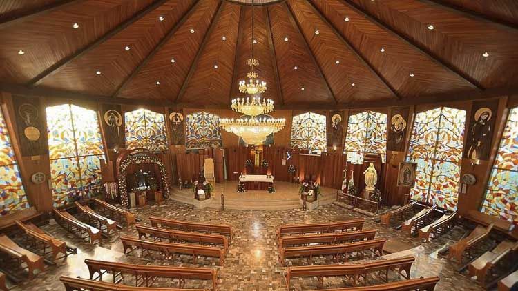 Interior de la Parroquia Nuestra Señora del Líbano en Puebla, con vitrales religiosos y candelabro central de cristal cortado