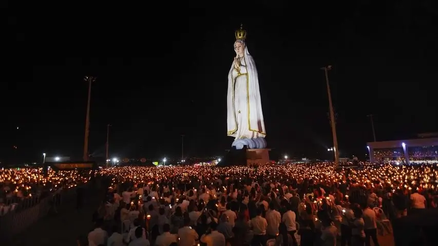 peregrinación nocturna con velas frente a la estatua gigante de la Virgen de Fátima en Brasil.
