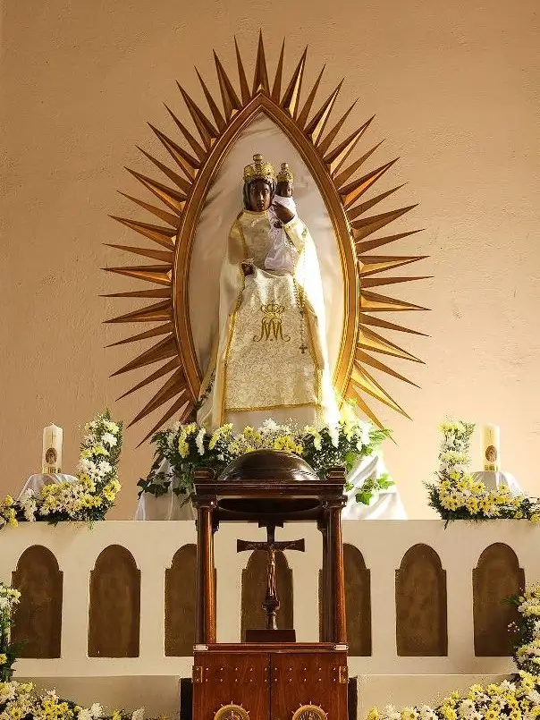 Estatua de la Virgen Negra de Letnica y el Niño Jesús, coronados, sobre el altar mayor de la iglesia en Kosovo, rodeados por un halo de rayos dorados ante quien santa madre teresa comprendió que su destino era servir 