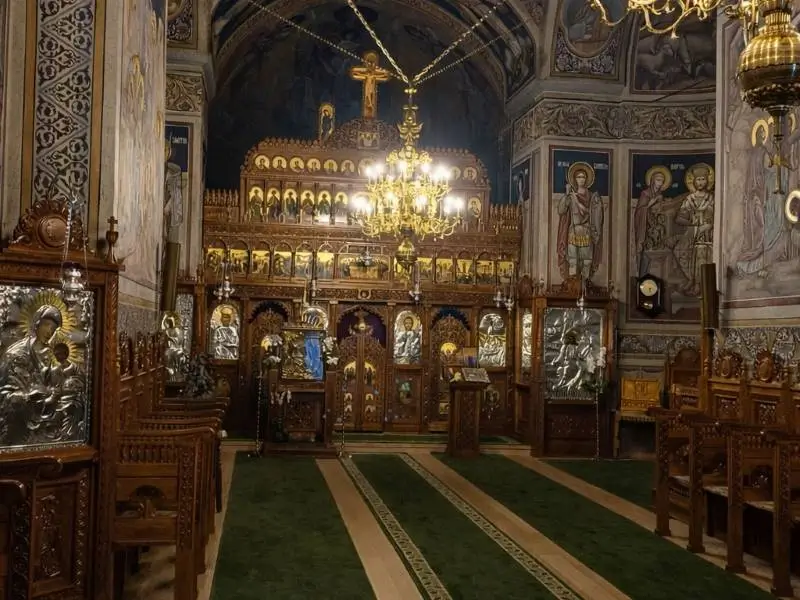 La imagen muestra el interior del Monaseterio de Vladimirești, una iglesia ortodoxa, caracterizado por su iconostasio de madera tallada, que es la pared de iconos y separaciones que divide el santuario del resto de la iglesia. 