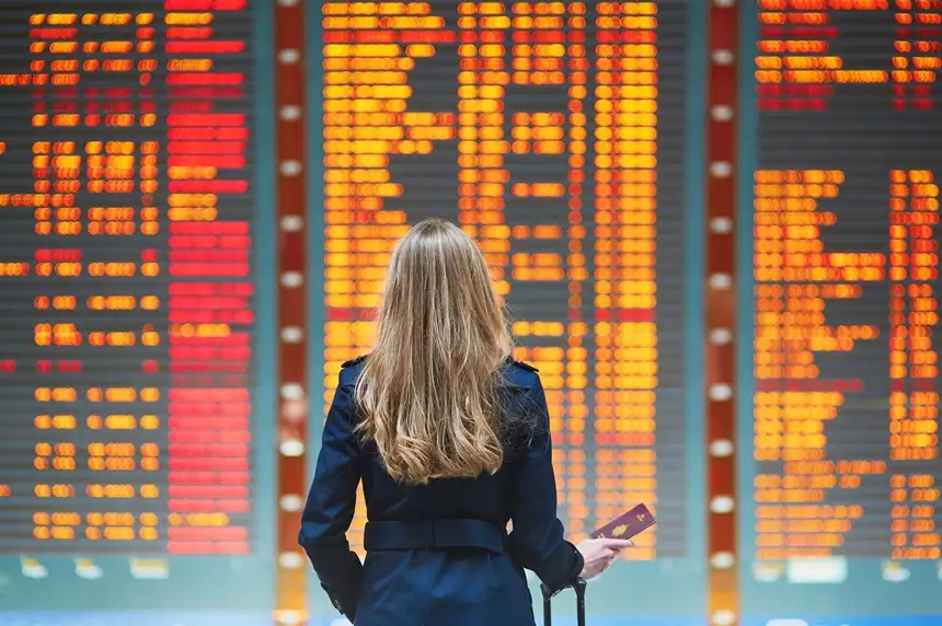 mujer parada frente a un cartel en un aeropuerto con pasaporte en la mano y el etias resuelto