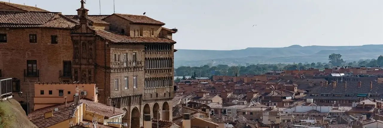 Esta imagen muestra una vista panorámica de la ciudad medieval de Tarazona, en Zaragoza, destacando el Palacio Episcopal de estilo renacentista que domina el paisaje urbano.