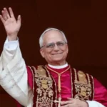 Esta imagen muestra al Papa León XIV, anteriormente conocido como Robert Francis Prevost, saludando desde el balcón de la Basílica de San Pedro