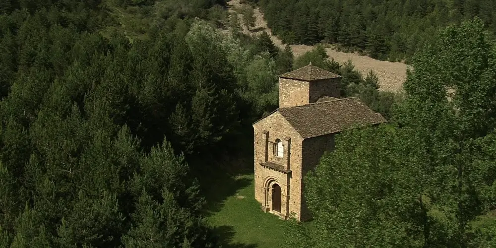 La imagen muestra la iglesia de Santa María de Iguácel, un destacado templo del románico aragonés del siglo XI situado en el fondo del valle de la Garcipollera, en la provincia de Huesca, España