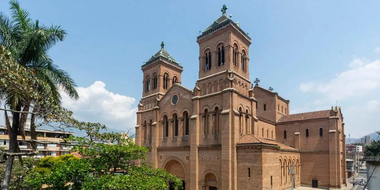 La imagen muestra la imponente Catedral Basílica Metropolitana de Medellín, ubicada frente al Parque Bolívar en Colombia. Este templo católico destaca por ser una de las construcciones en ladrillo macizo (adobe cocido) más grandes del mundo, diseñada en estilo neorrománico por el arquitecto francés Charles Émile Carré