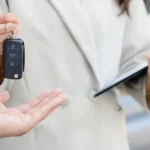 La imagen es una fotografía de stock genérica que representa la entrega de las llaves de un auto (compra, venta, alquiler o renting) en palermo
