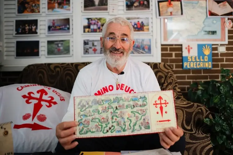La imagen muestra a Manuel Rossi, el creador y promotor del Camino de Uclés, sosteniendo un mapa ilustrado a mano y una credencial de esta ruta jacobea que conecta Madrid con el Monasterio de Uclés en Cuenca